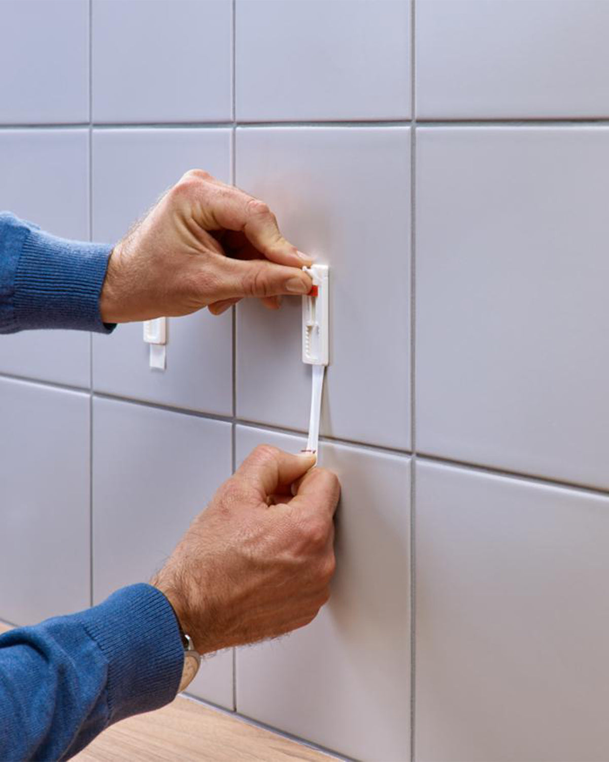 En häftremsa dras nedåt vid borttagning av Tesa kakelspik från kakel